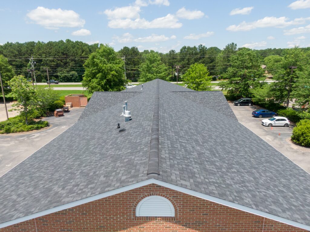 A roofer in action on a steep roof, installing asphalt shingles.