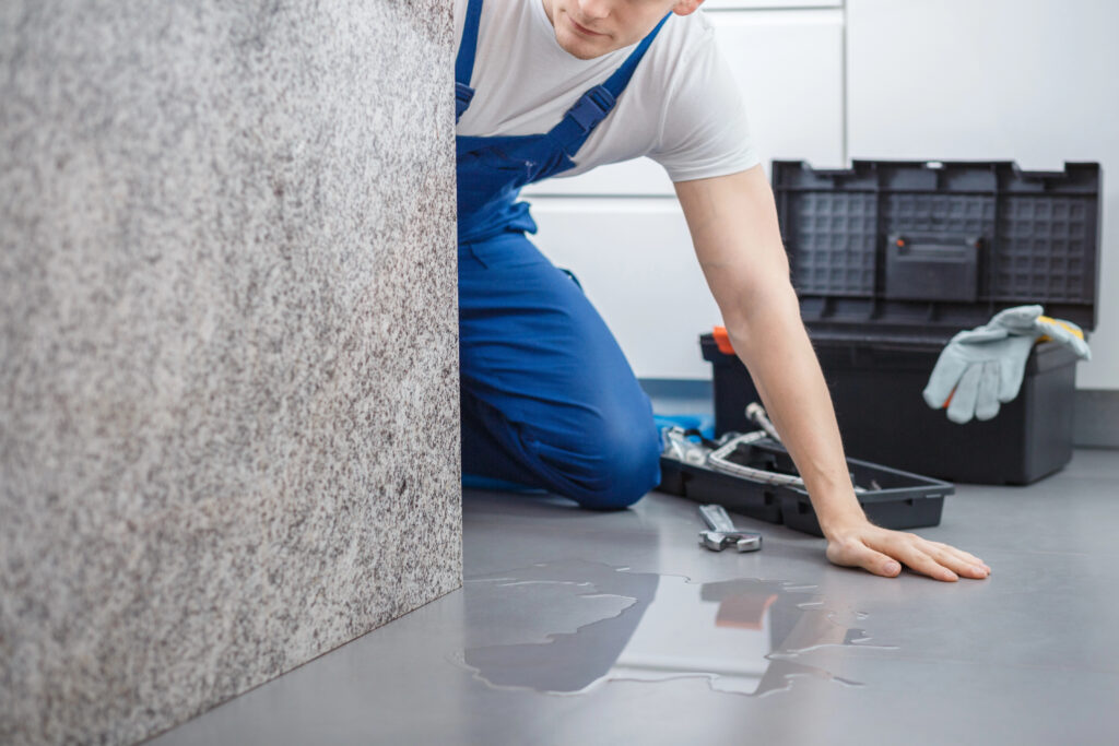 Plumber from Sawtooth Plumbing & Heating Inc. repairing plumbing inside a home with tools and gloves
