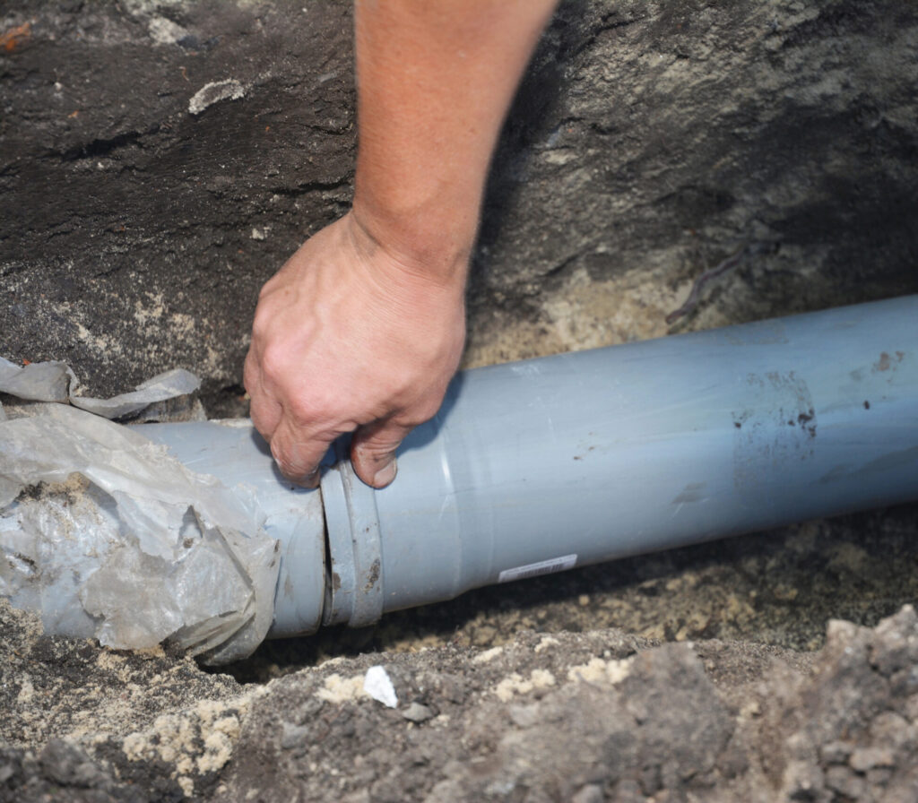Plumber repairing a buried water pipe with a coupler using Sawtooth Plumbing & Heating Inc. service