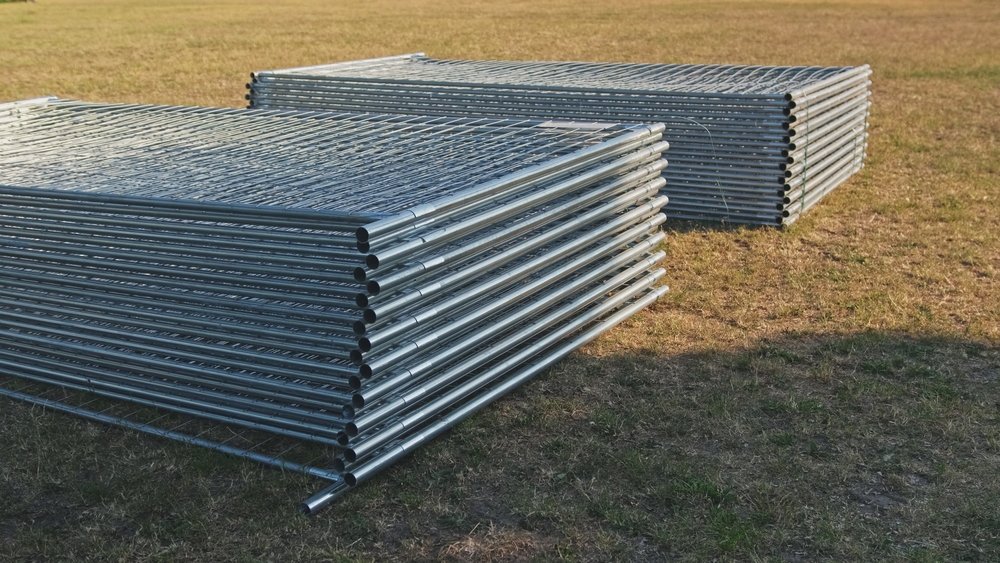 Stacked steel pipes and lumber bundles outdoors in a field for Jim's Lumber
