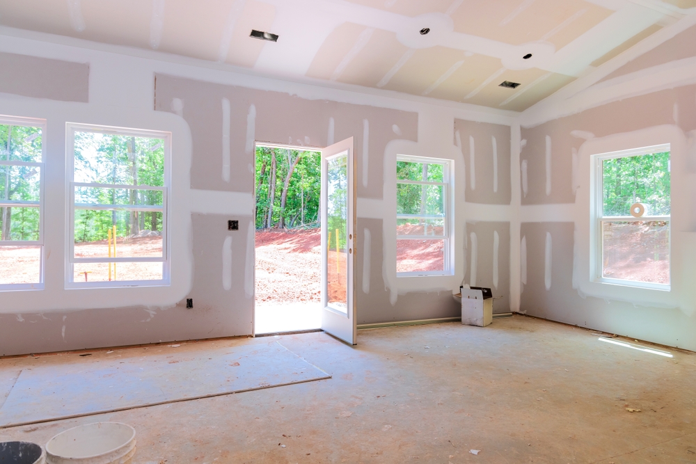 Jim's Lumber interior drywall installation with open door and windows during home construction