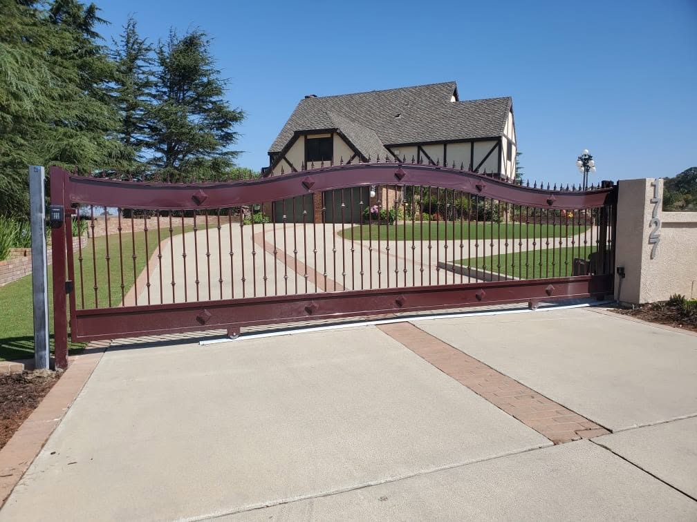 Pacific Overhead Door Service image of a maroon automatic driveway gate and house exterior
