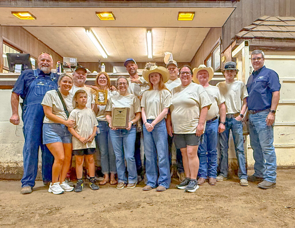 Midwest Texas Longhorn Association group photo of members holding awards and trophies inside a barn