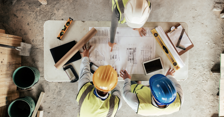 Three people discussing the plan at a building site